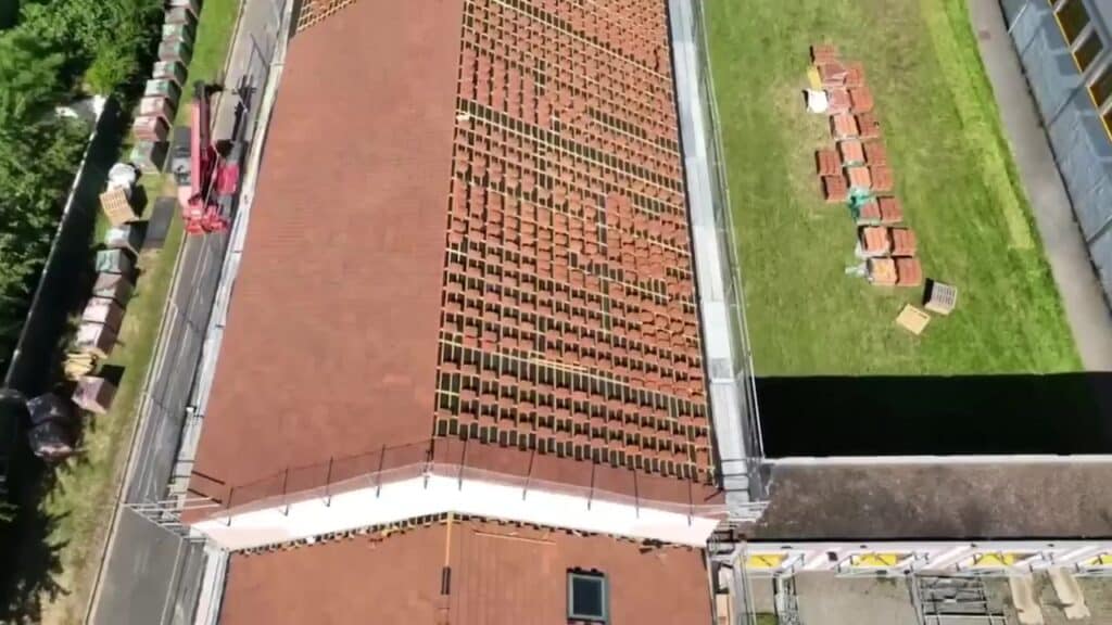 Toiture du collège de Neuilly-en-Thelle vue du drone, tuiles en partie déposées et palettes de tuiles neuves au pied du bâtiment